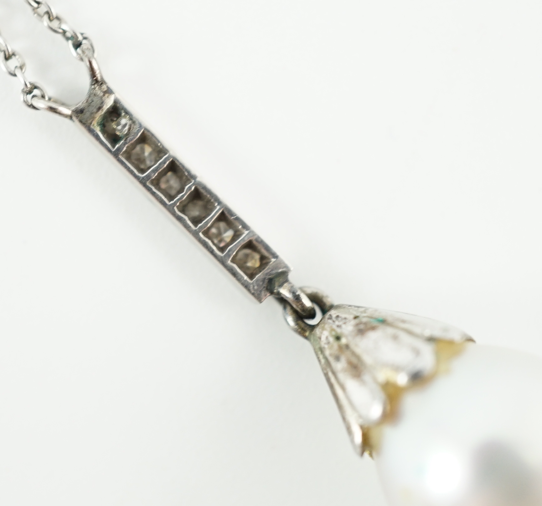 A 1920's platinum, single stone pear shaped cultured pearl and six stone diamond chip set pendant necklace